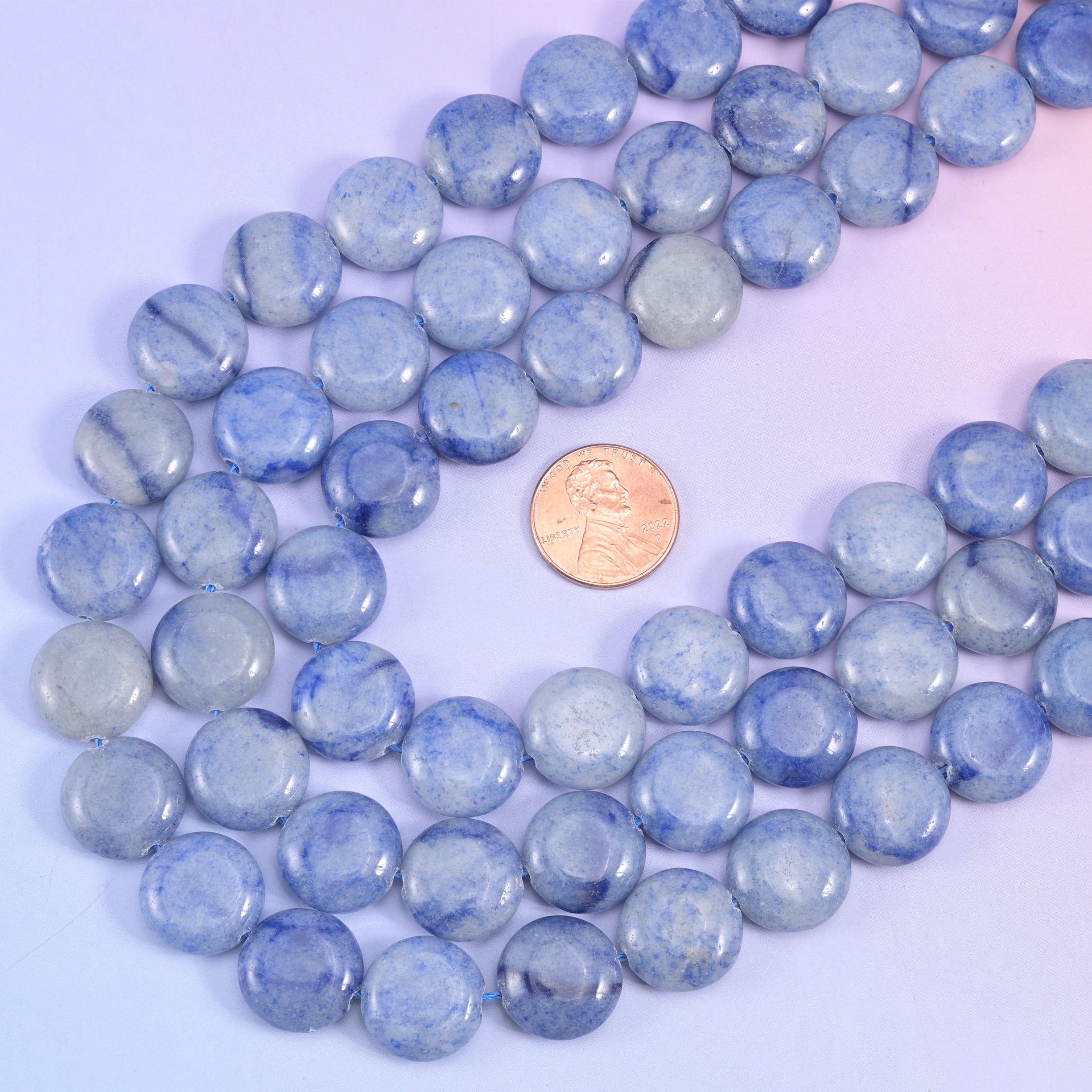 Blue aventurine coin strands looped around a US penny for size comparison with the 15mm beads