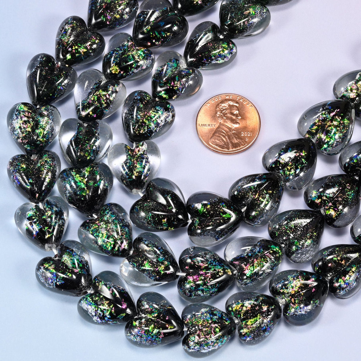 Puffed glass heart beads with dark iridescent surface and colourful flecking