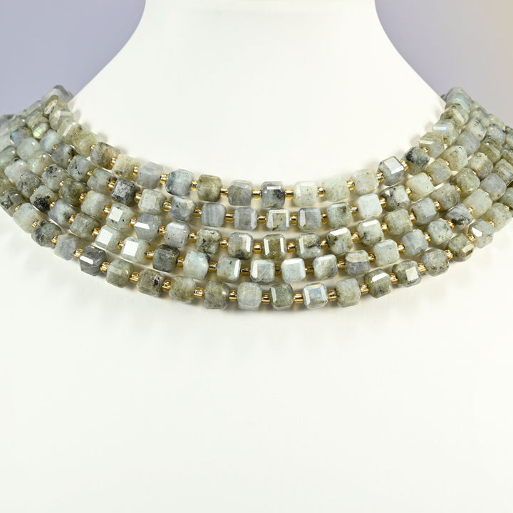 Gray labradorite faceted cube strands arranged as a layered collar on a white display bust, sage gray beads across the neck