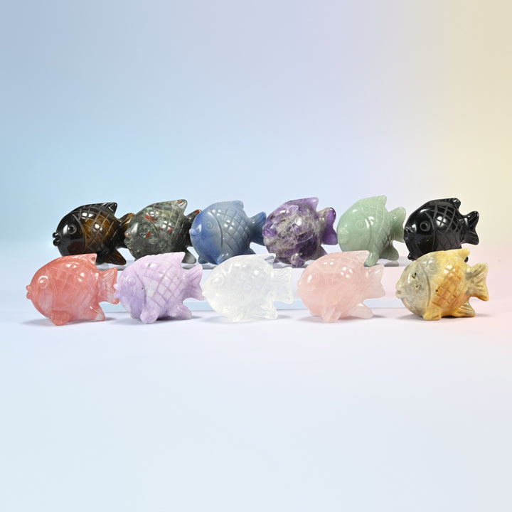 Eleven 1.5 inch tropical fish crystal carvings in natural stones and cherry quartz, arranged in two rows