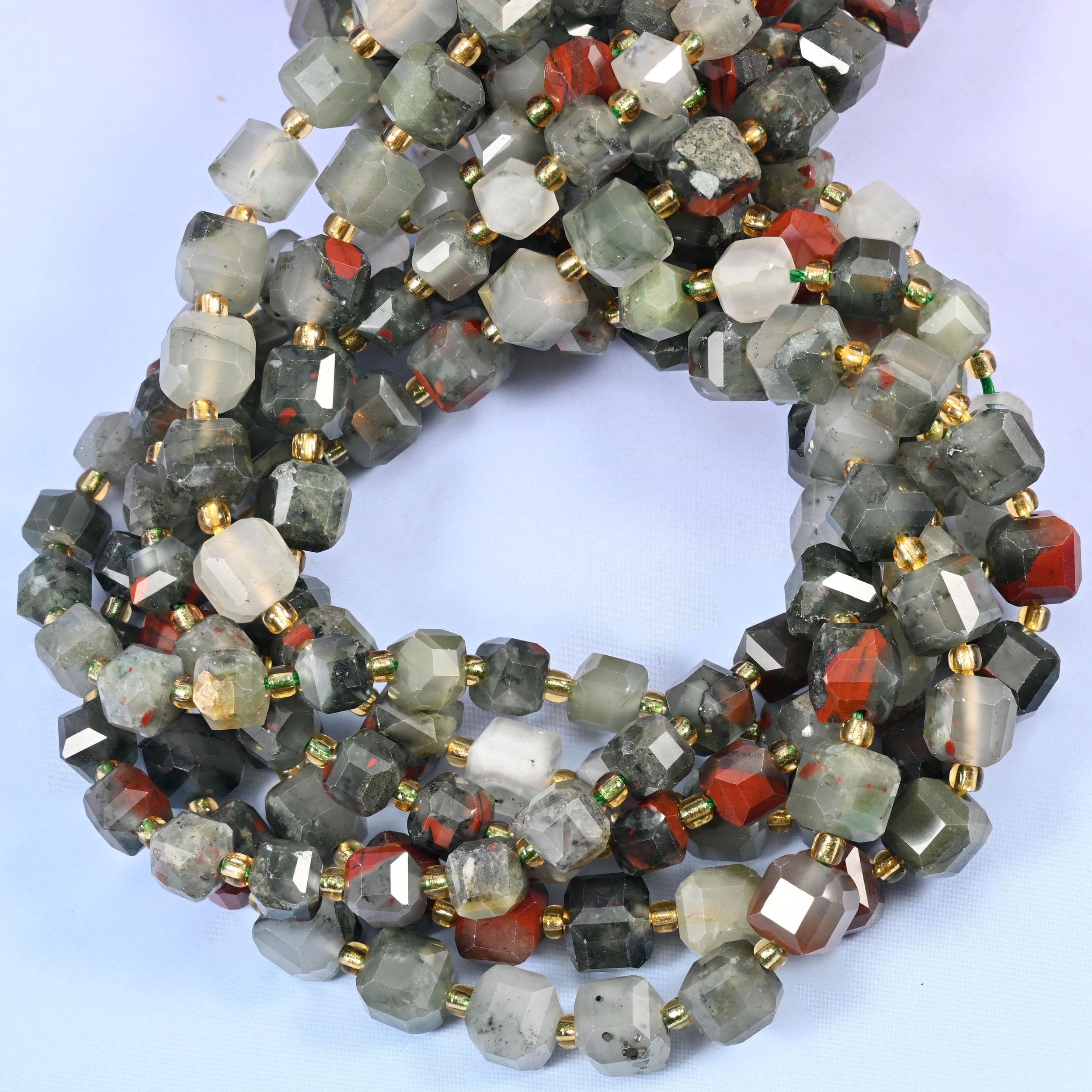 Smoky grey-green cubes, some almost translucent, punctuated along the strand by cubes of brick red and rust — the colour break that gives this stone its name