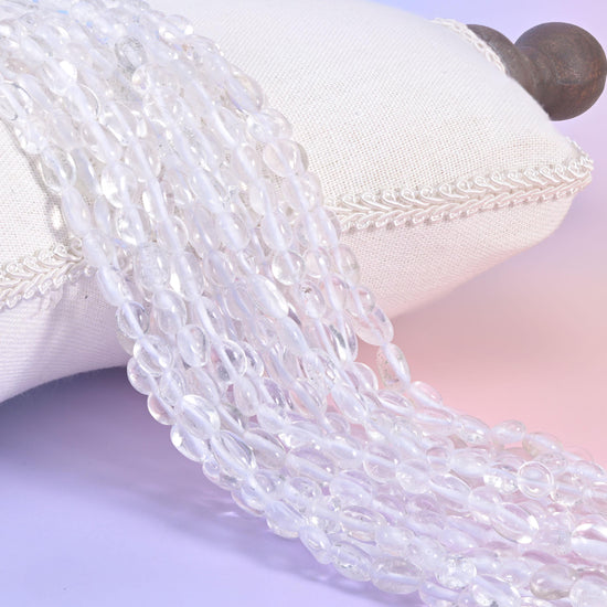 Clear quartz nugget strands on a white cushion, colourless glassy beads shot with milky veils