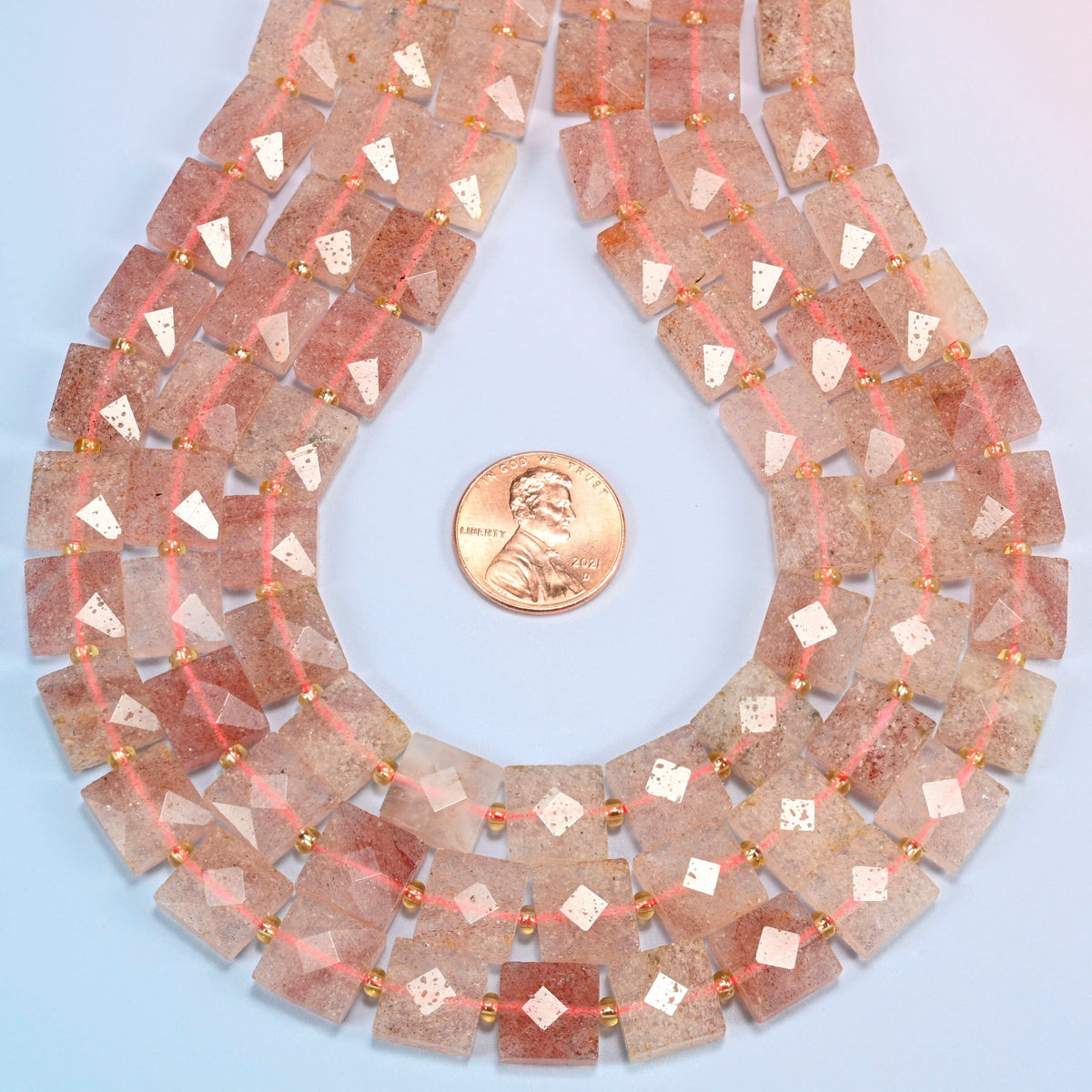 Natural strawberry quartz faceted flat square strands formed into a teardrop loop around a US penny for scale