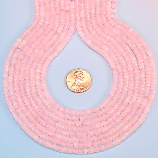 Rose quartz faceted heishi disc strands formed into a teardrop loop around a US penny for scale