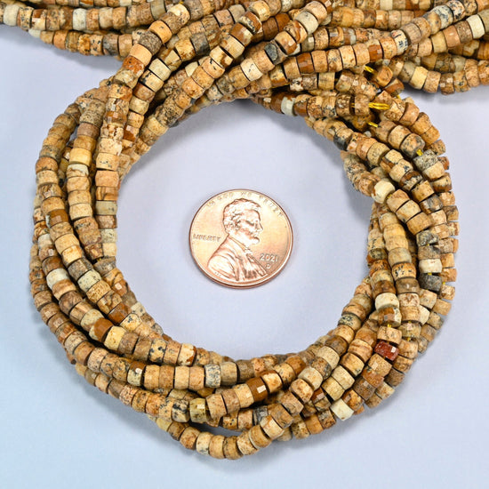 Picture jasper faceted heishi disc beads 2x4mm coiled in a loop around a US penny for scale, close-up of the faceted disc shape