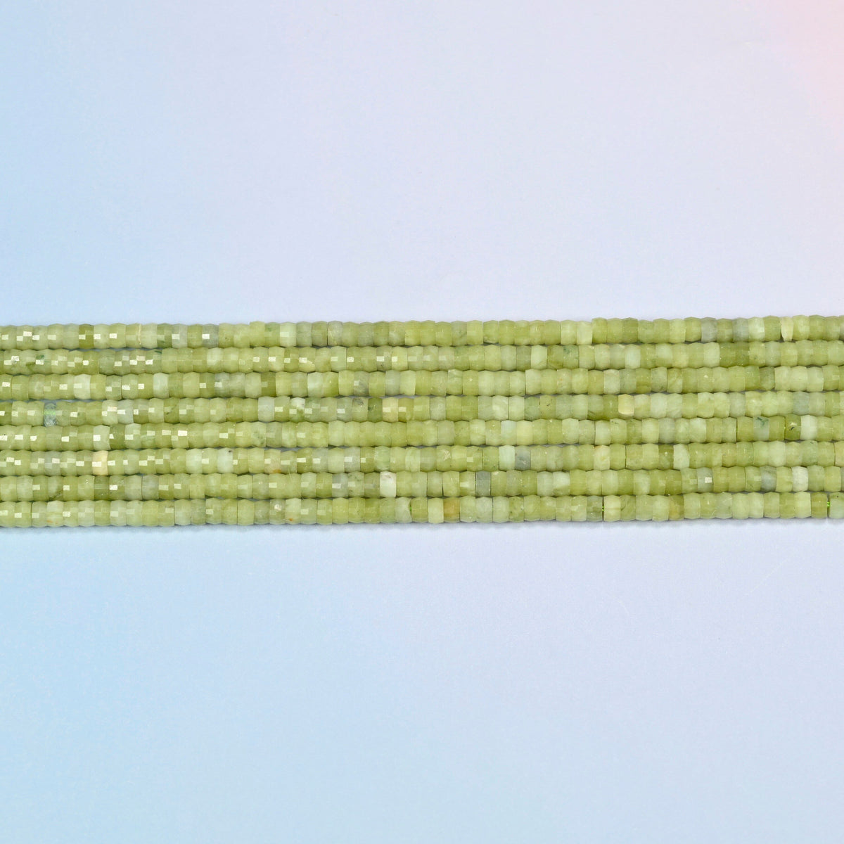 Several strands of South Jade faceted heishi disc beads laid in straight rows
