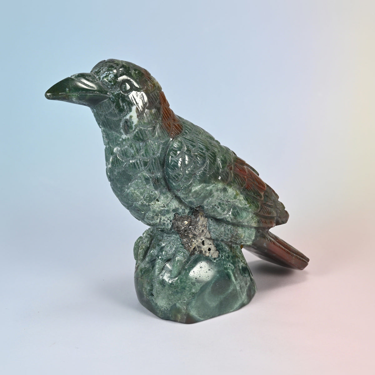Three-quarter view of the natural Indian agate crow carving facing left on its rock base