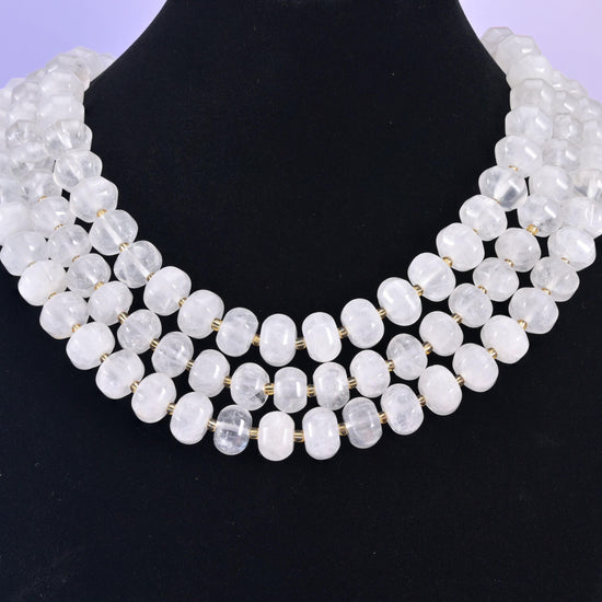 Rondelles on a black display bust, milky white beads standing out against the dark backdrop