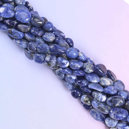 Diagonal run of Sodalite pebble beads across a pale lavender background