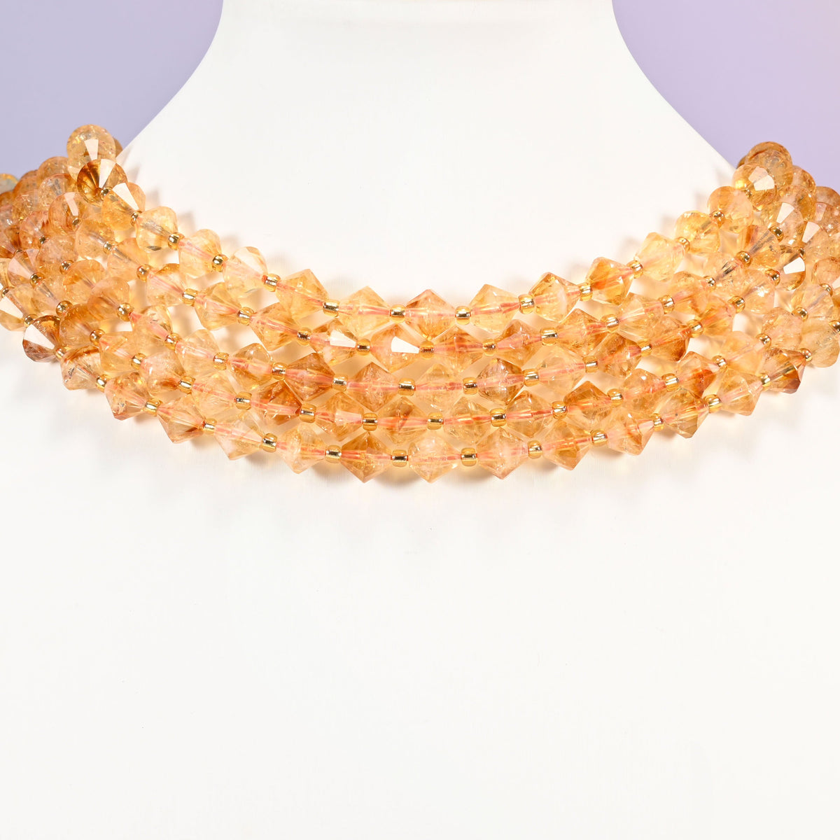 Citrine bicone beads curved into a collar, light passing through the beads and warming the whole strand.