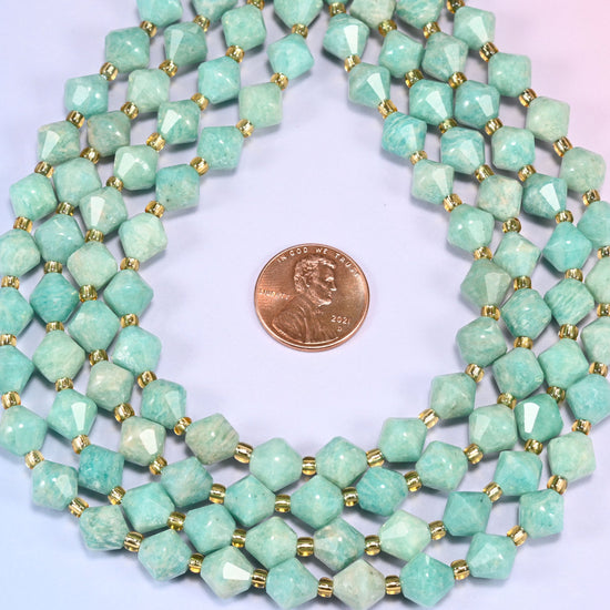 Green Amazonite faceted bicone beads 8mm with gold-tone spacers, strand coiled into a neat circle with a penny centered for scale