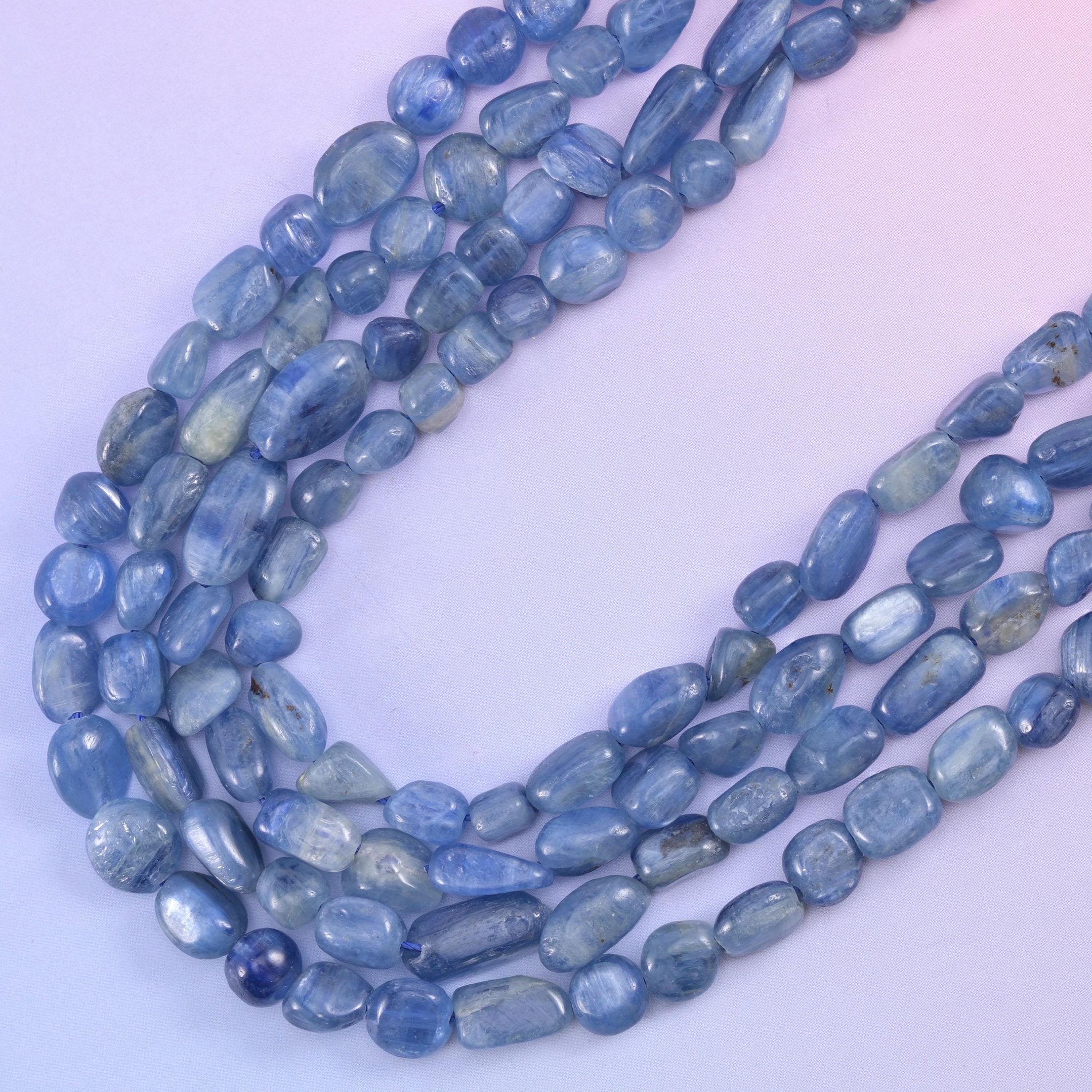 Loose loops of kyanite nuggets from above, colour shifting between grey-blue and deeper denim