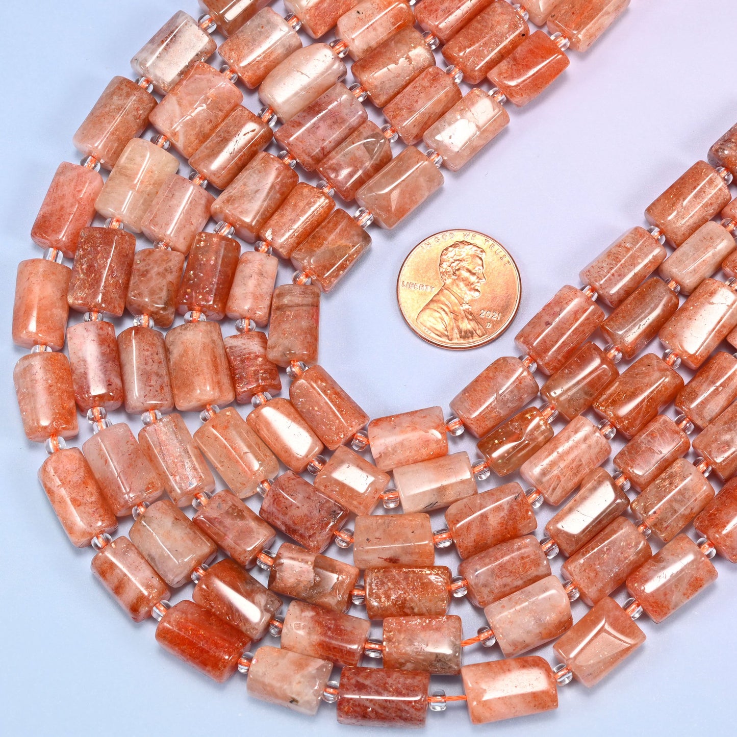 Close-up of coiled Golden Strawberry Quartz tube beads with clear glass spacers, showing the natural stone texture and glowing color variation.