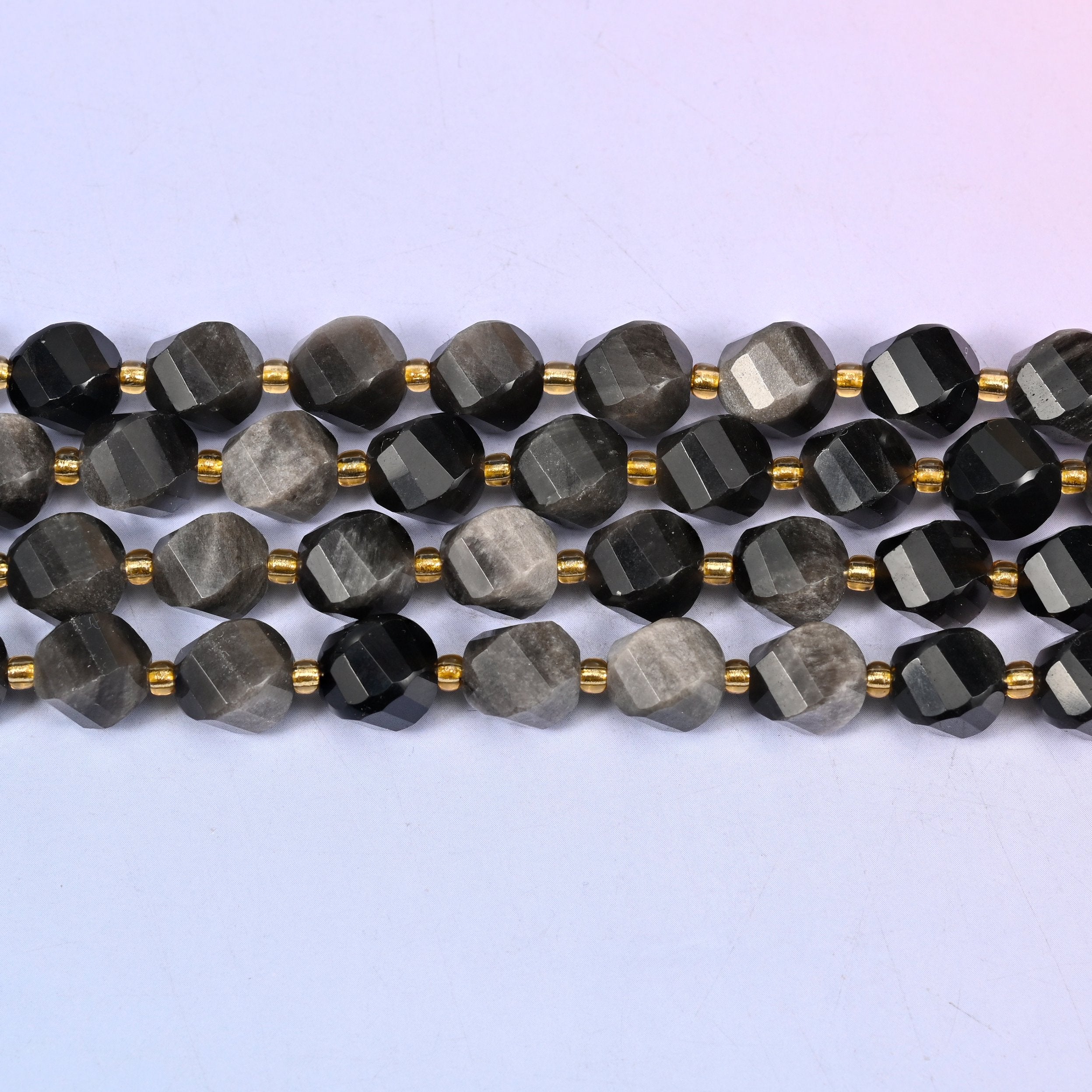 Silver Obsidian natural stone beads with some beads flashing brightly beside others reading as solid charcoal