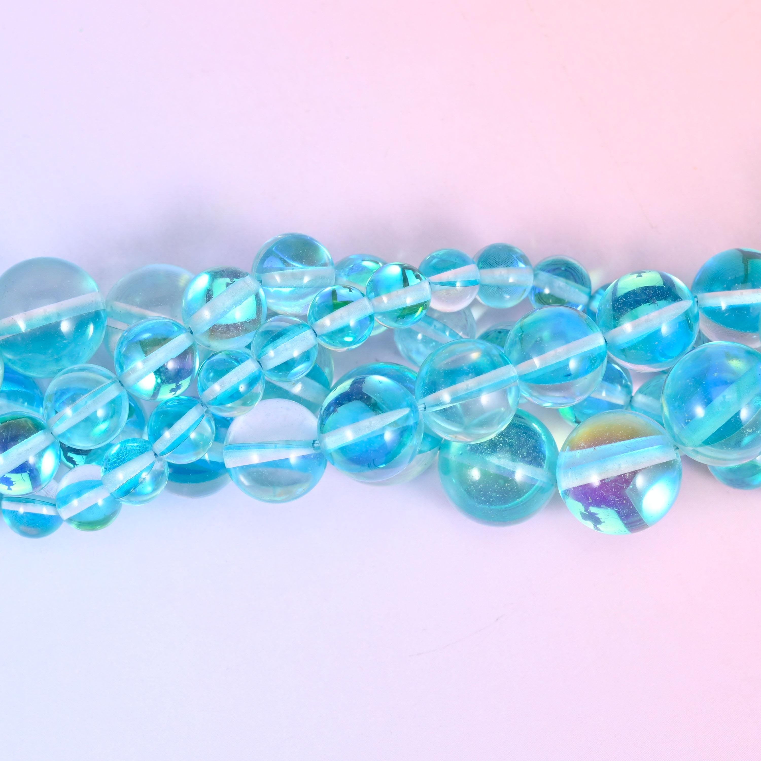 Clear aqua and sky blue rounds with a glossy polished surface, lit from inside by a green-blue rainbow flash