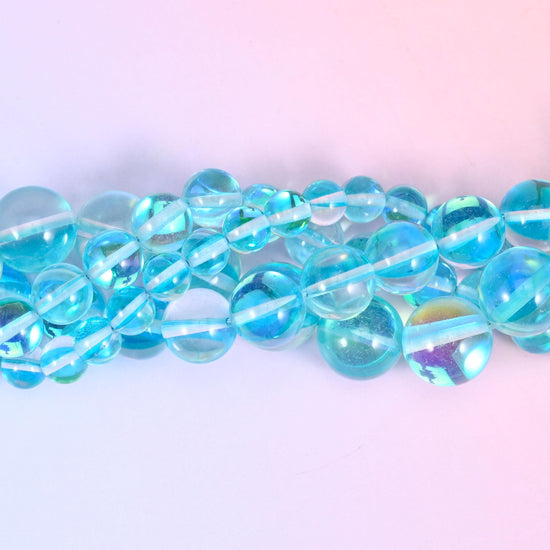 Clear aqua and sky blue rounds with a glossy polished surface, lit from inside by a green-blue rainbow flash