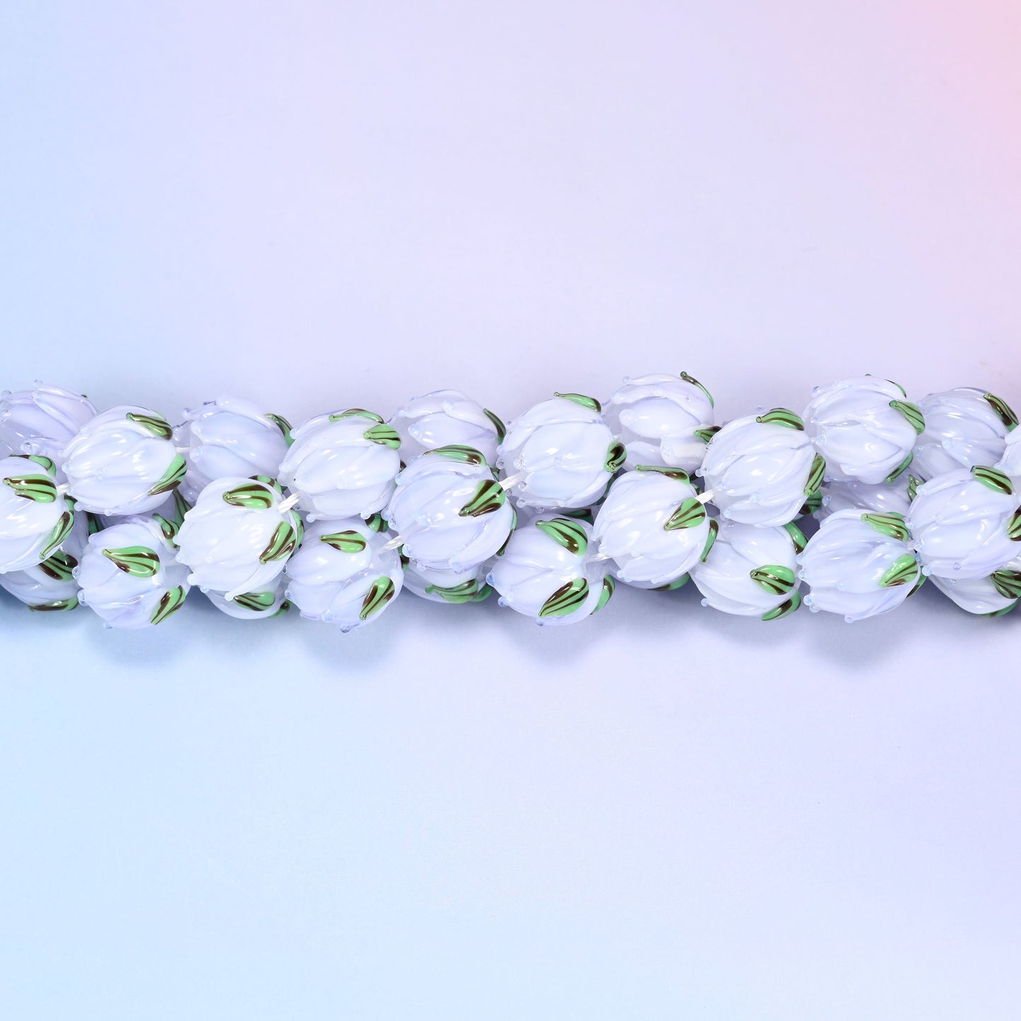 Light purple tulip bud-shaped lampwork glass beads, hand-formed with sculpted petal detailing that gives a realistic flower bud look, accented with a green leaf detail at the base.