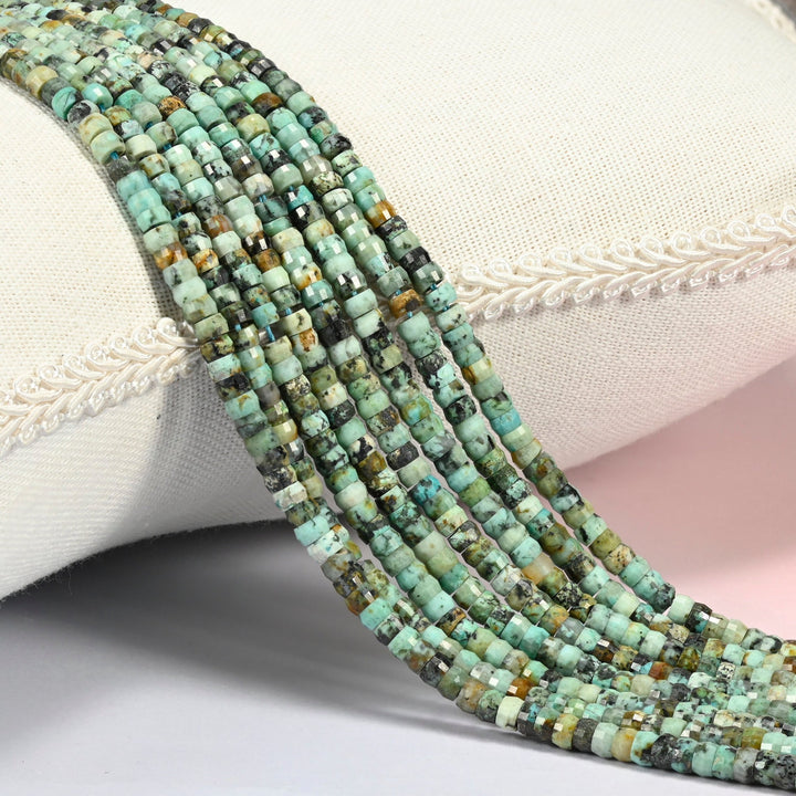 African howlite faceted heishi disc beads 2x4mm, several strands draped over a white cushion