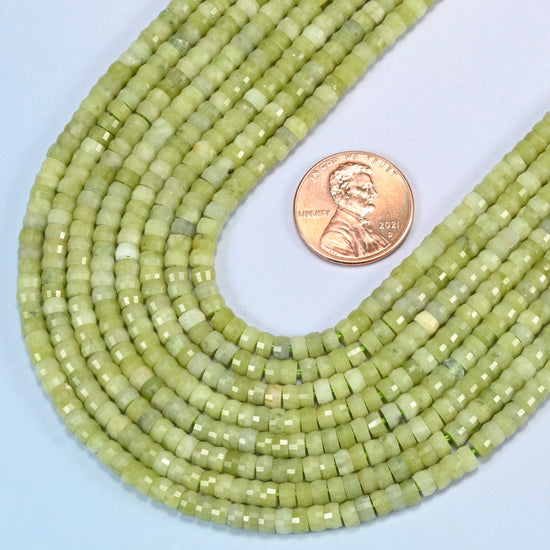 Close view of South Jade faceted heishi disc strands curving beside a US penny for scale