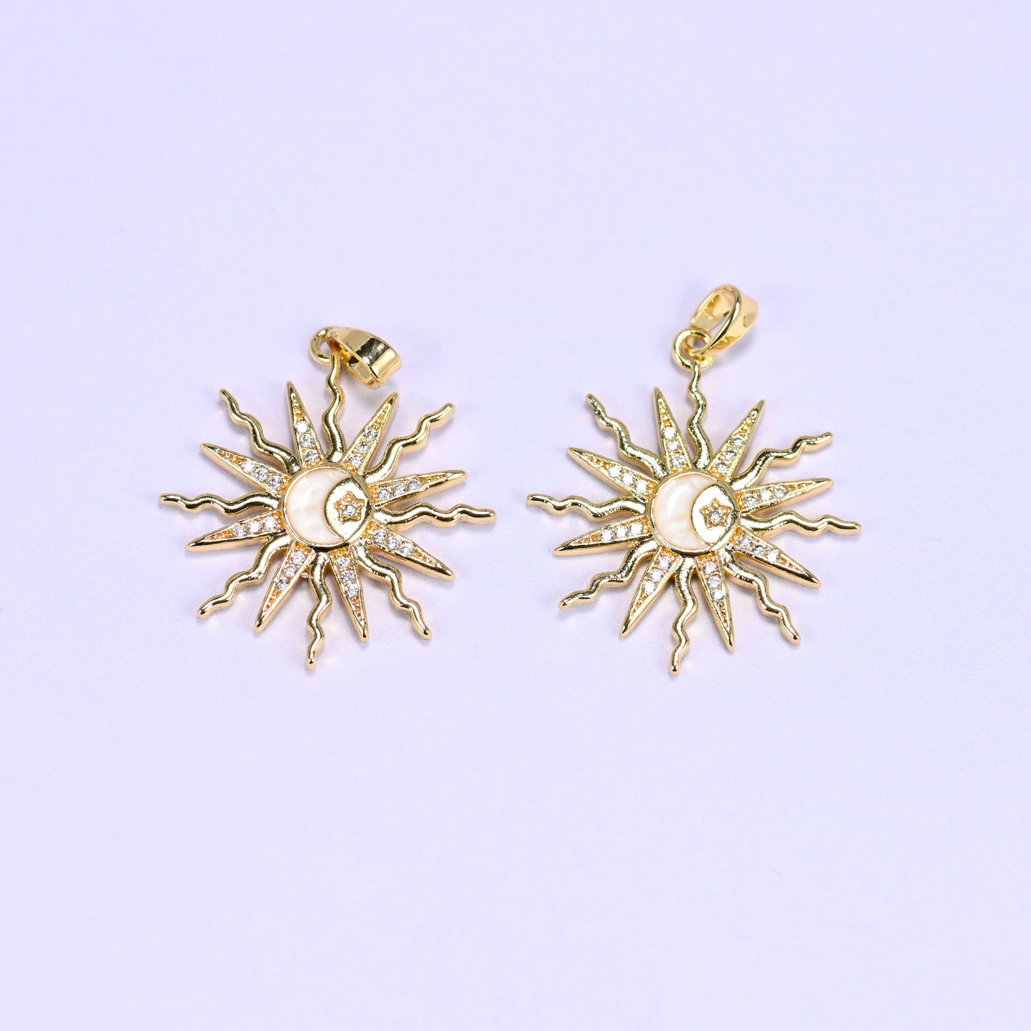 Two enamel moon sun zirconia charms with cream-white enamel centres, gold rays paved in clear zirconia around a crescent and star.