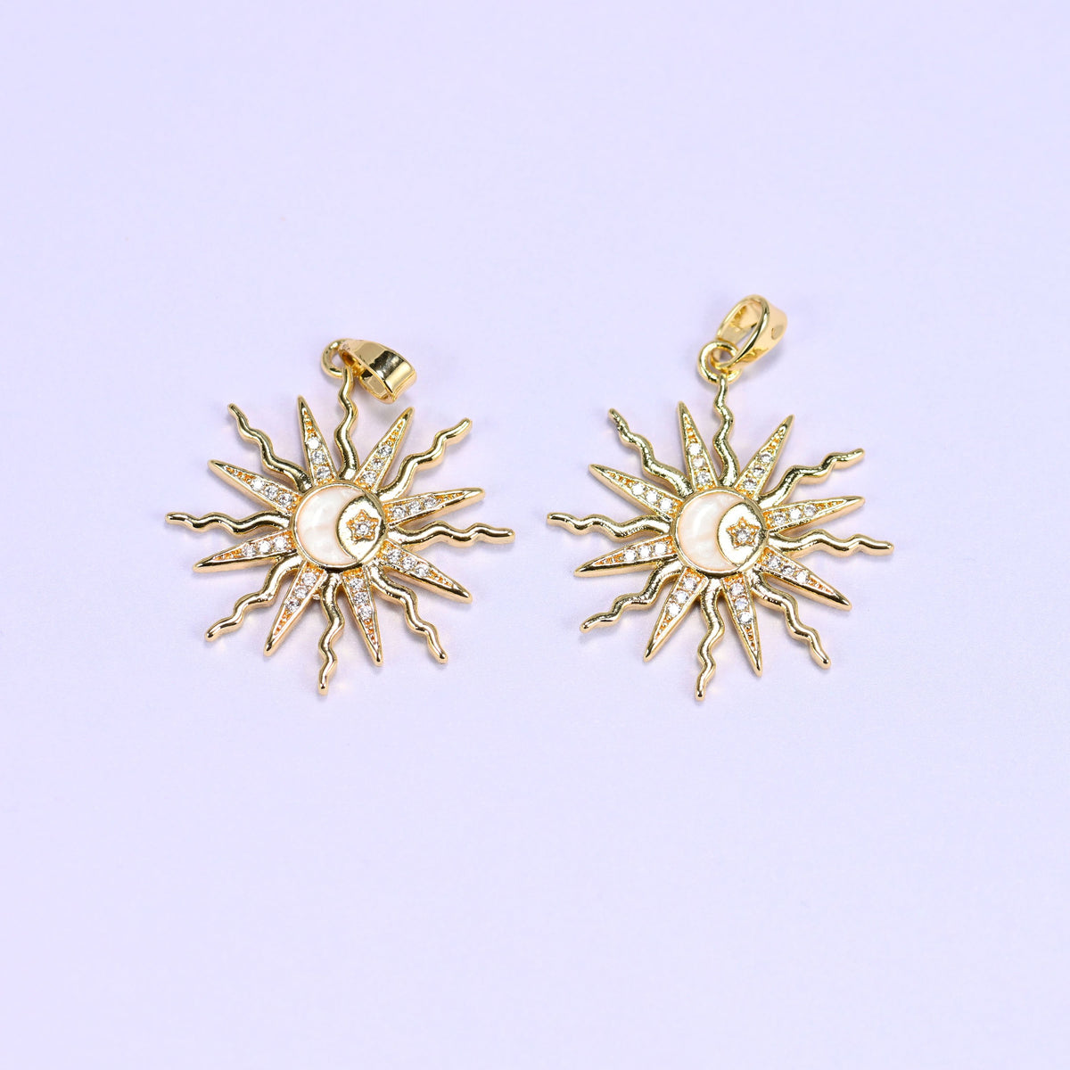 Two enamel moon sun zirconia charms with cream-white enamel centres, gold rays paved in clear zirconia around a crescent and star.