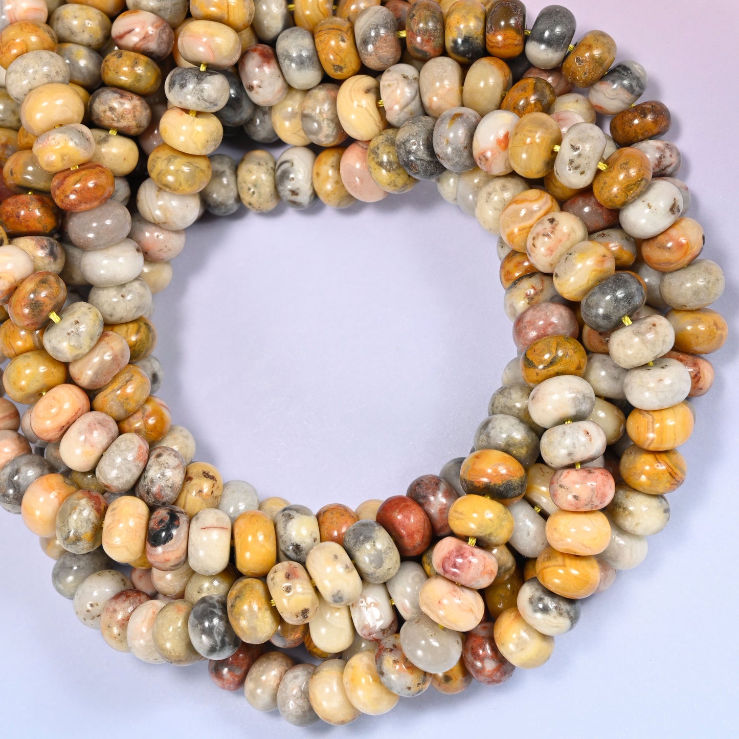 Close-up horizontal row of Crazy Agate beads showing the mustard and cream stone pattern.