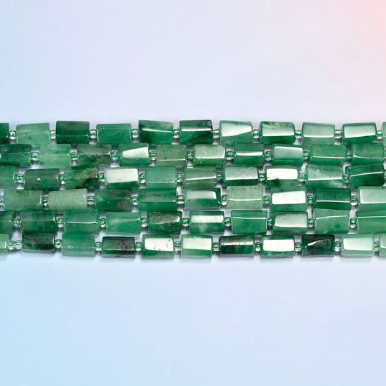 Several strands of African jade faceted tube beads laid in straight rows with light green seed bead spacers