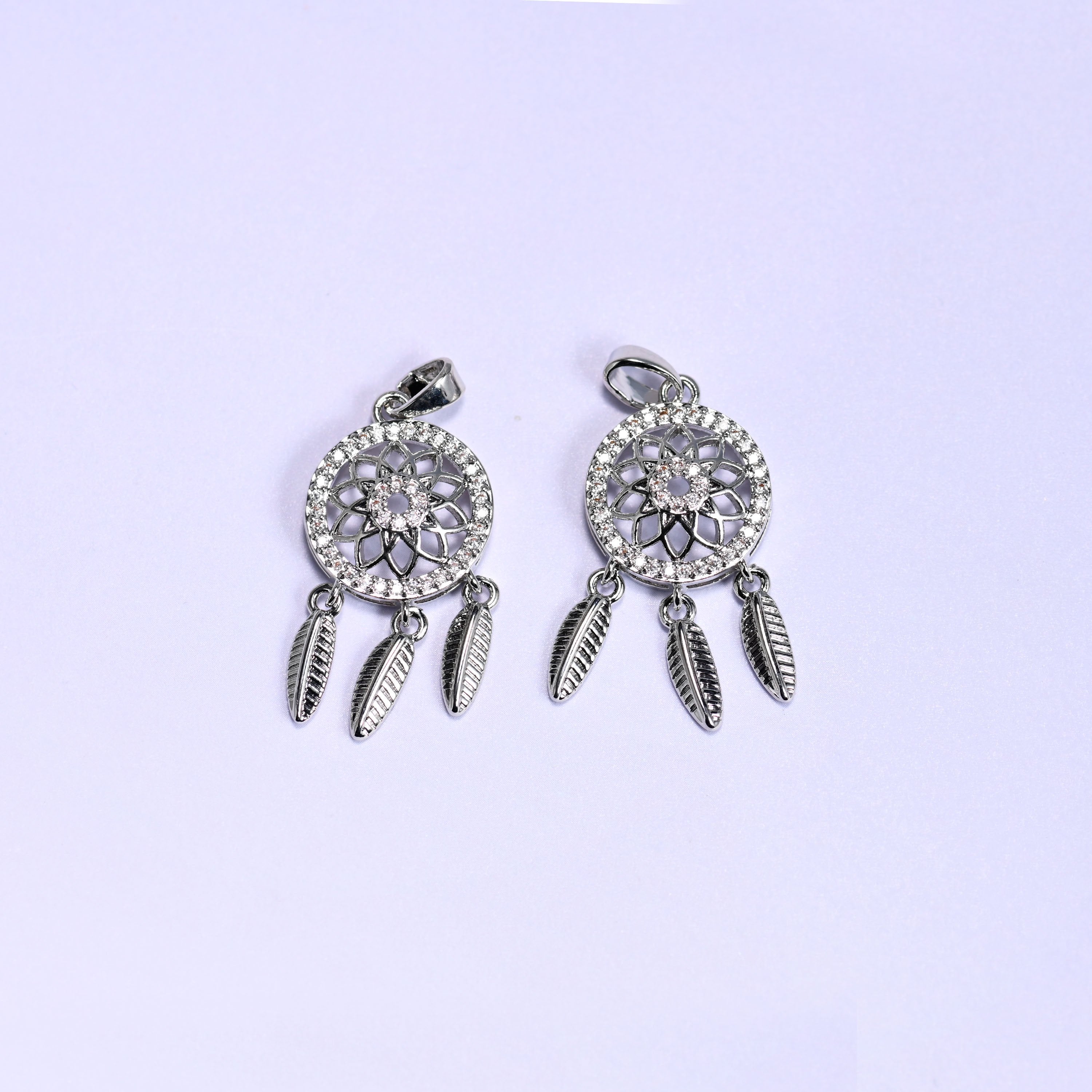 Dream Catcher Zirconia Charms in silver tone, two platinum plated pendants with openwork floral medallions, zirconia pave rims and three feather dangles each.