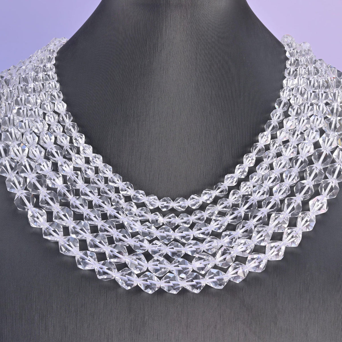 Clear Quartz diamond star cut beads on a black display bust, the facets catching the light