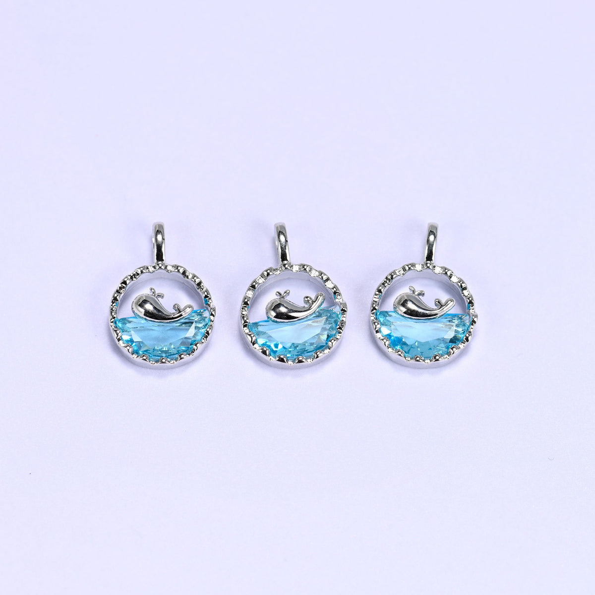 Whale charm with a silver whale silhouette diving into a faceted blue zirconia wave