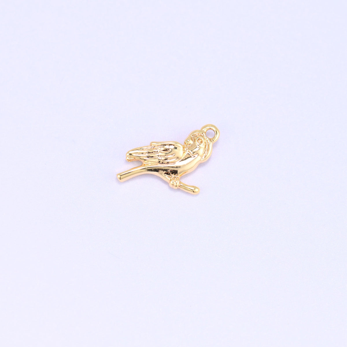 Small gold charms bird, single 18K gold plated brass charm perched on a branch, side view