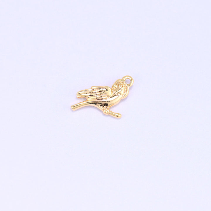 Small gold charms bird, single 18K gold plated brass charm perched on a branch, side view