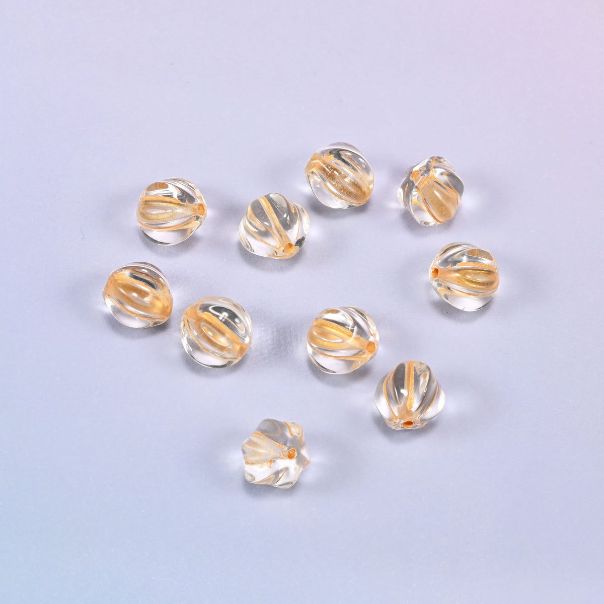 A scattered group of loose 8mm clear gold pumpkin glass beads, showing the melon ribs and the drill holes.