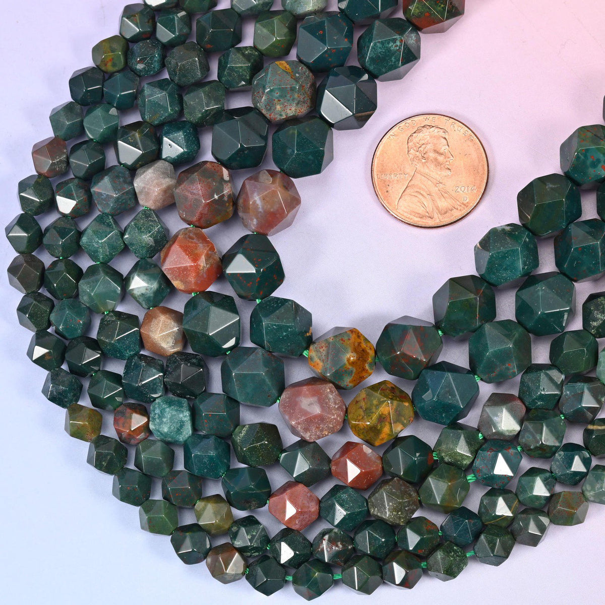 Indian Bloodstone star cut beads with a US penny alongside for size reference, available in 6mm, 8mm and 10mm