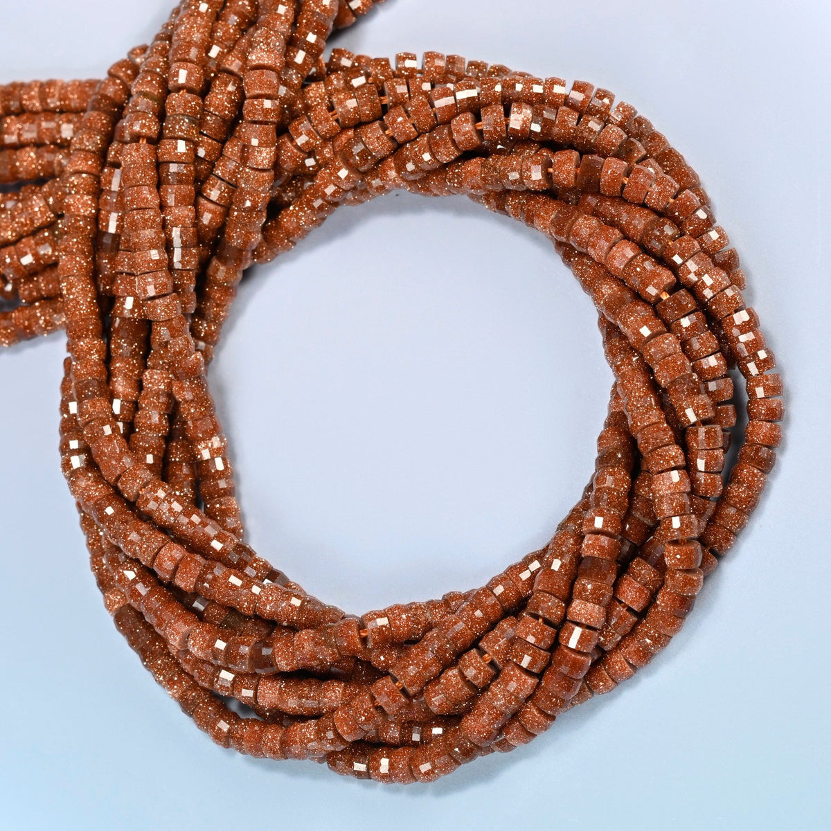 Gold sandstone faceted heishi disc beads coiled into overlapping loops, whole strands of sparkly copper glass