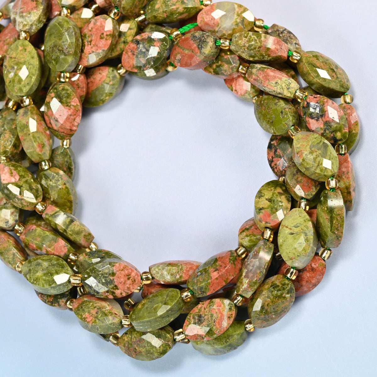 Unakite faceted flat oval beads coiled into overlapping loops, whole strands of green and pink stone