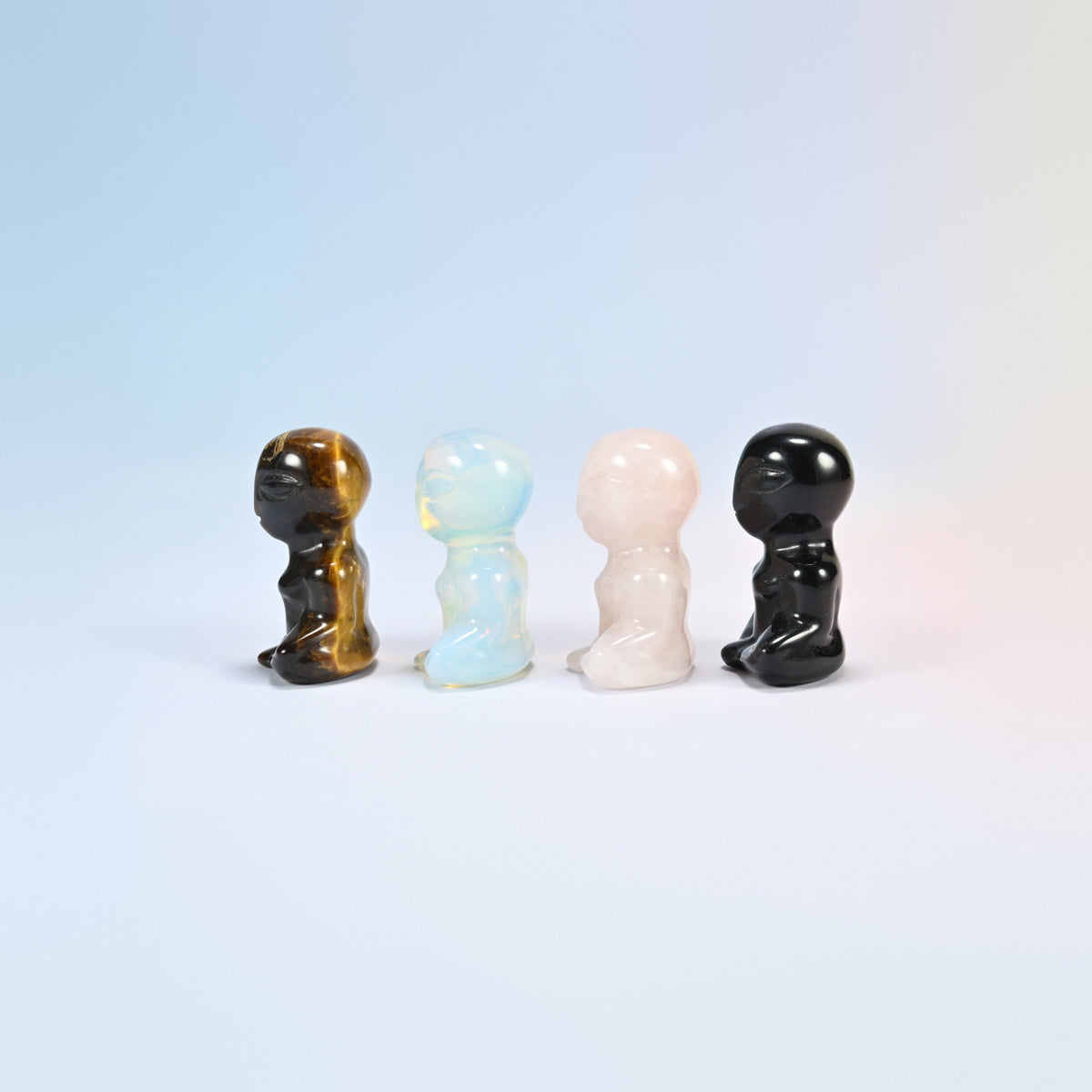 Four small crystal aliens turned to the side in brown, white, pink and black stone