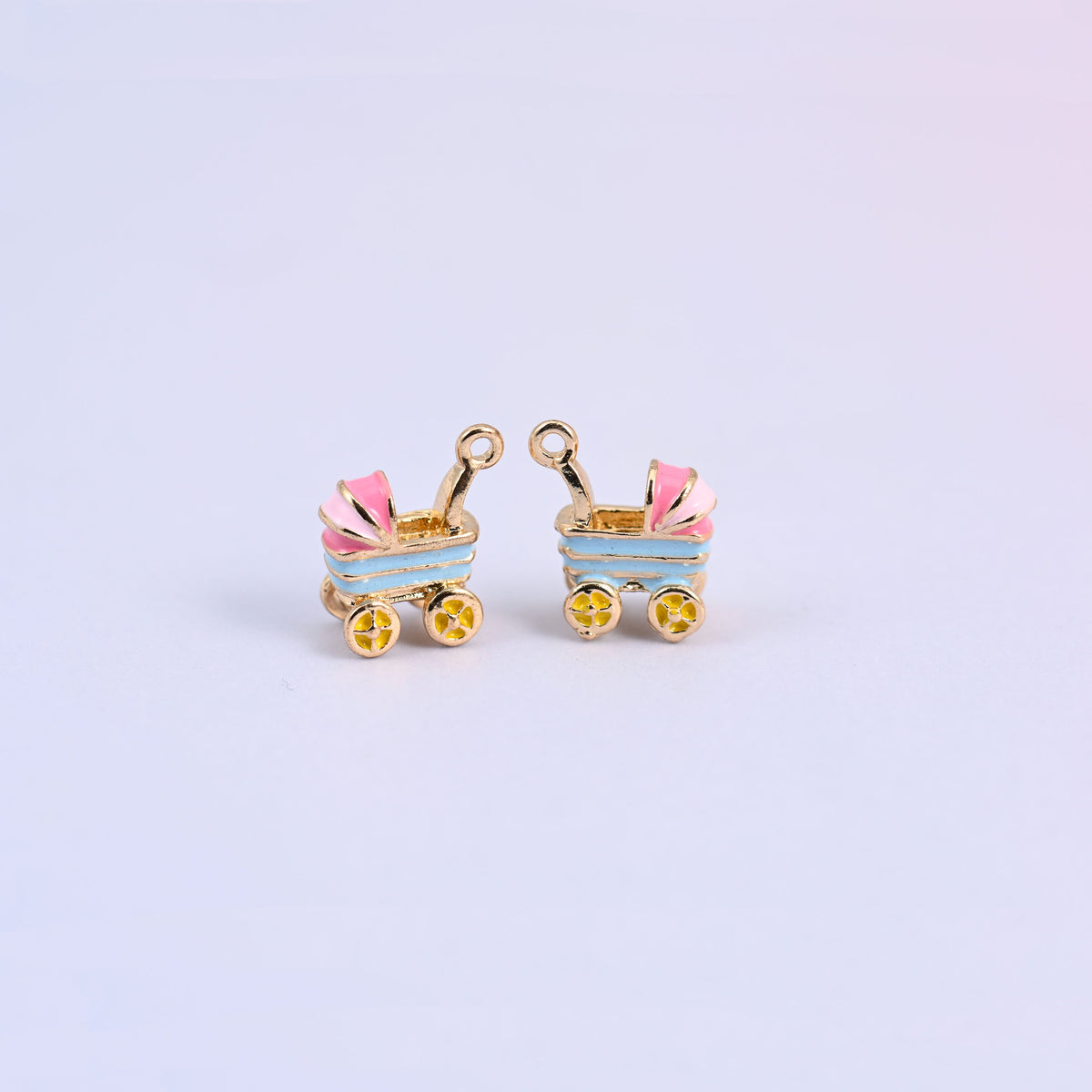 Two light blue stroller charms with pink striped hoods and yellow flower-spoke wheels, enamel over 18K gold plated brass.