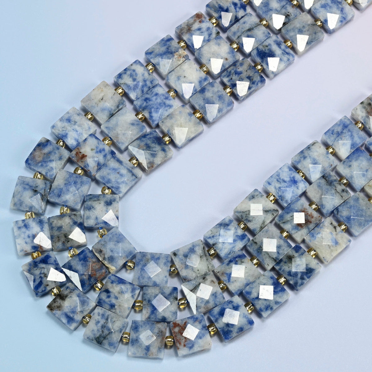 Natural blue spot jasper faceted flat square beads in several strands curved into a wide U, white stone with blue spots