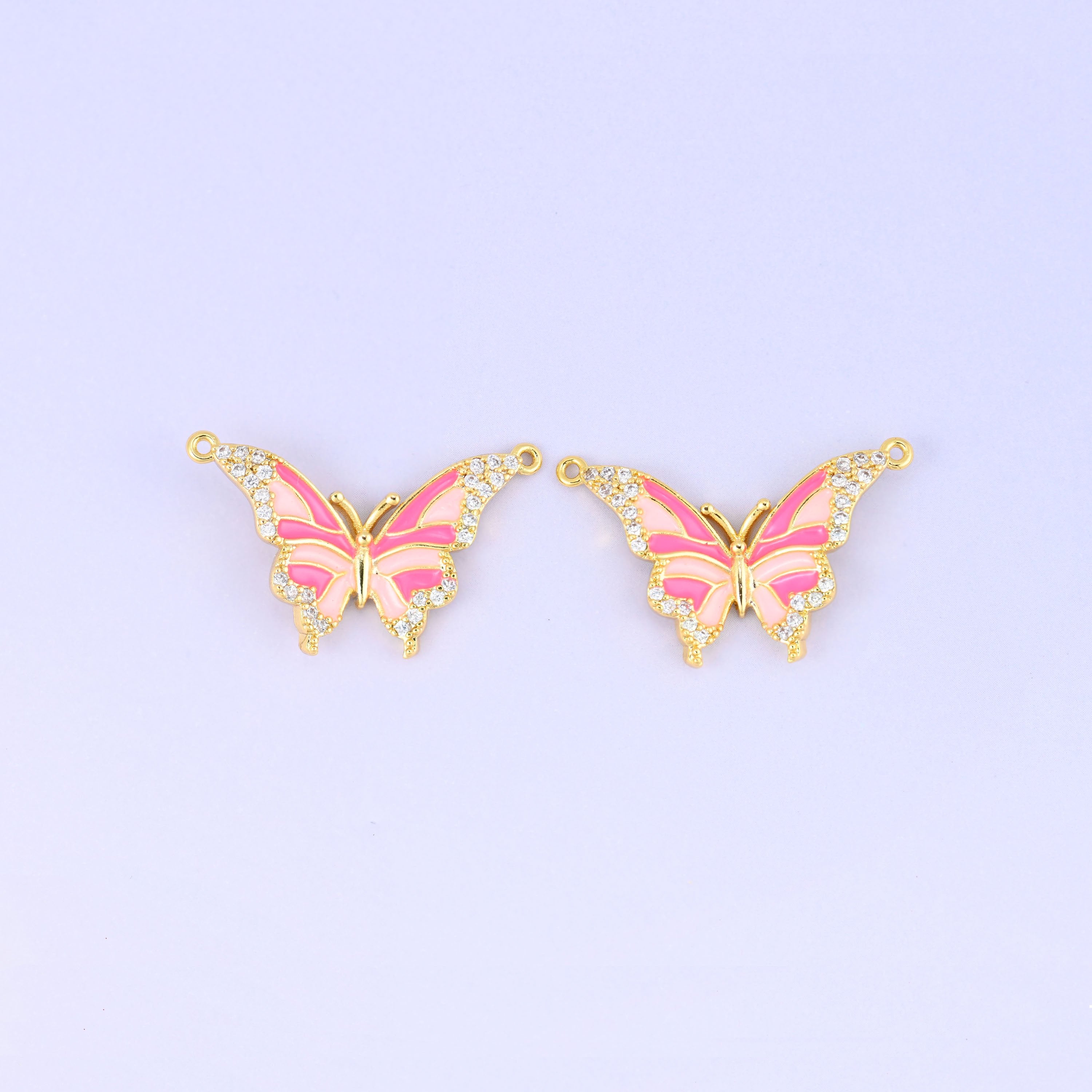 Enamel butterfly double connector pendants in pink, two gold plated charms with hot pink and blush wing stripes and a loop at each upper wing tip.
