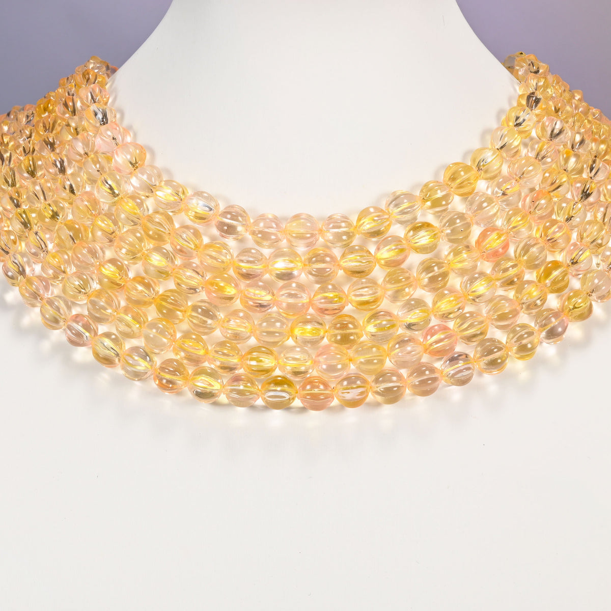 Yellow clear pumpkin glass beads shown as layered strands on a white neck display form.