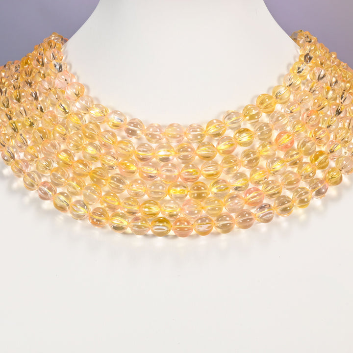Yellow clear pumpkin glass beads shown as layered strands on a white neck display form.