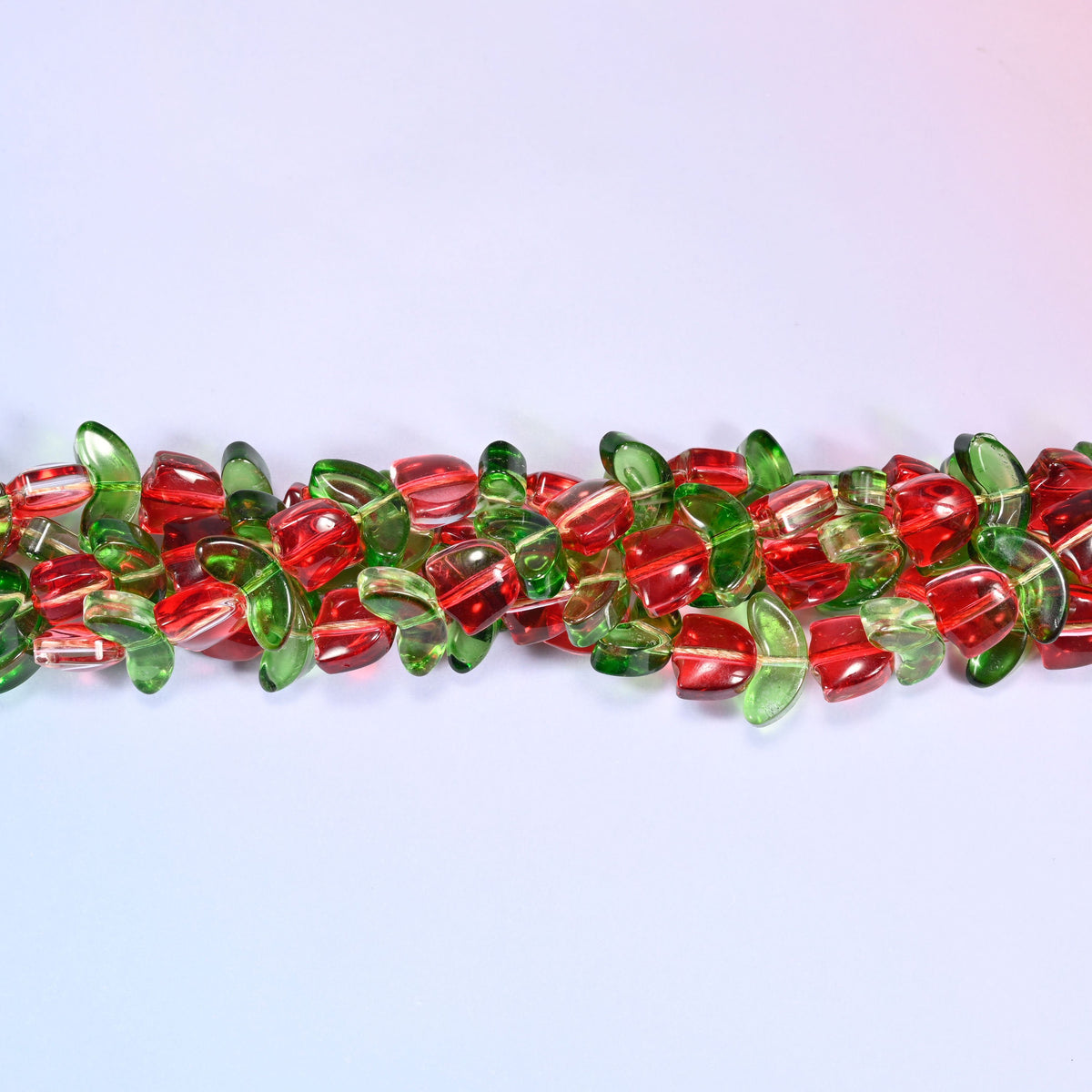 Red tulip flower-shaped glass beads paired with green leaf-shaped glass beads for botanical-inspired jewelry.