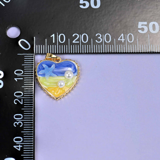 Enamel Heart Pendants measured against a black millimetre ruler, the blue charm reading close to 20mm wide.