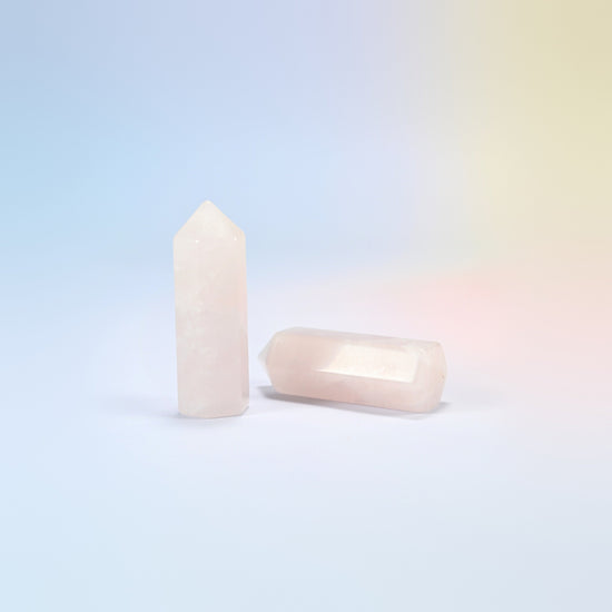 Natural rose quartz hexagon points in light pink, one standing and one lying down