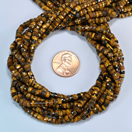 Tiger eye faceted heishi disc beads 2x4mm coiled in a loop around a US penny for scale, close-up of the faceted disc shape