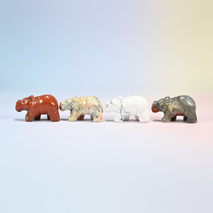 Side view of four gemstone hippopotamus figurines walking in a row
