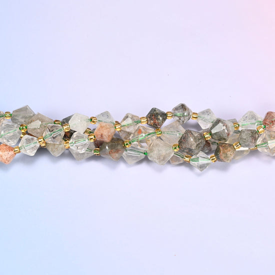 Macro close-up of Green Phantom Quartz faceted bicone beads on a strand, showing the faceted cut and gold-tone spacer beads.