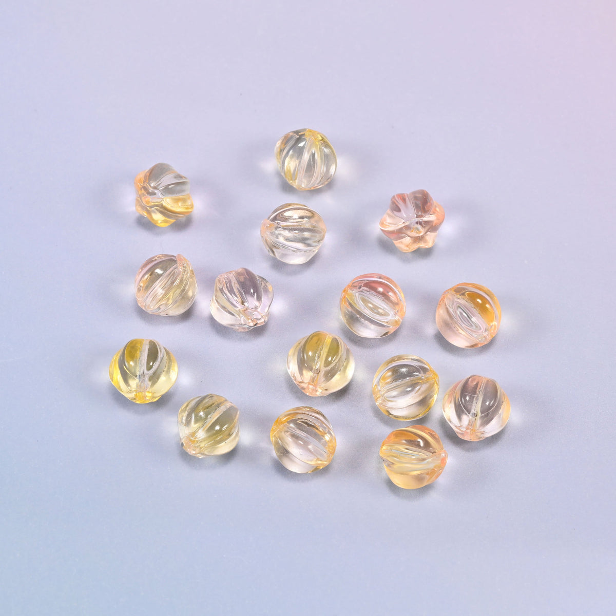A scattered group of loose 8mm yellow clear pumpkin glass beads, showing the melon ribs and the drill holes.