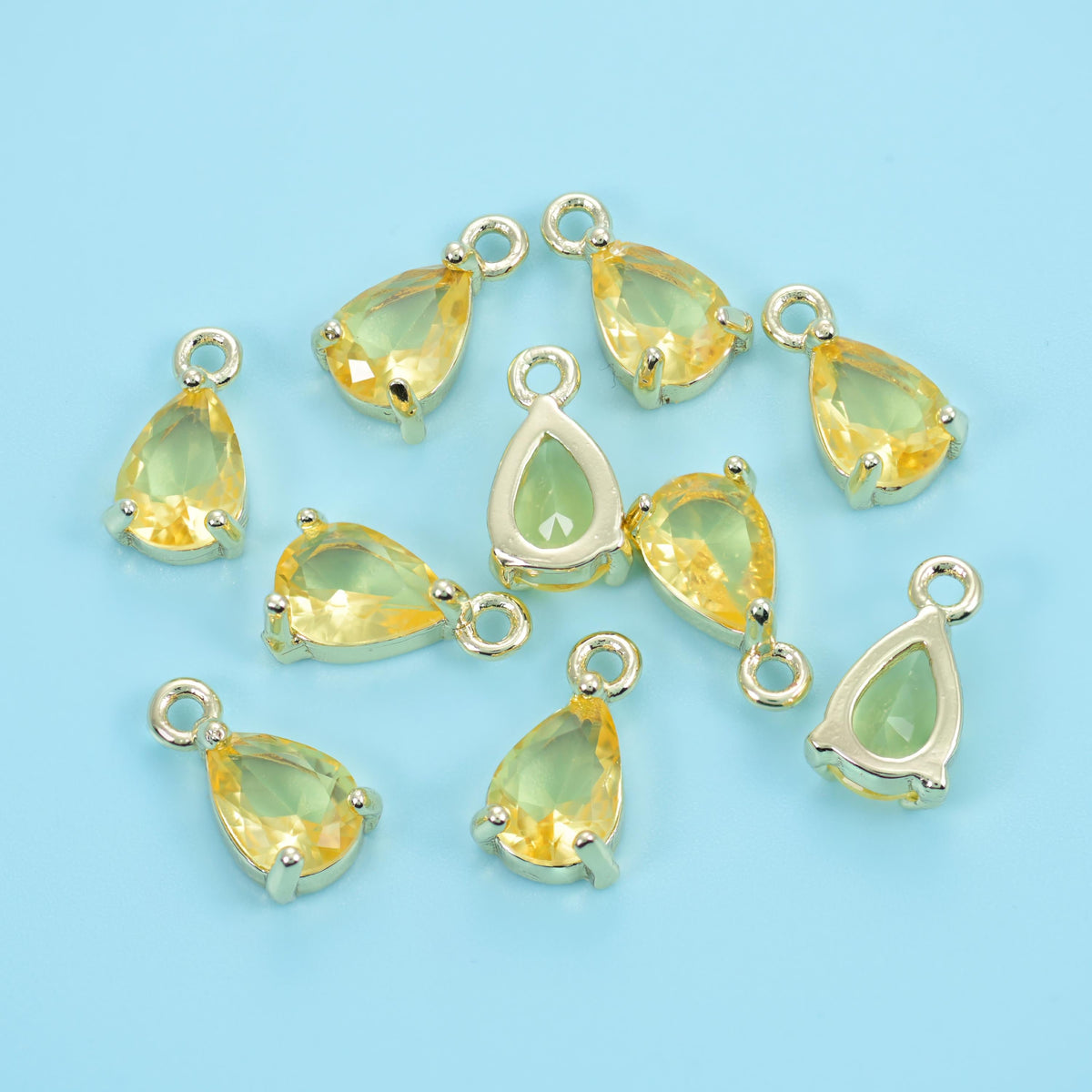 Teardrop zirconia charms in canary yellow, a scattered group of pear-cut stones.